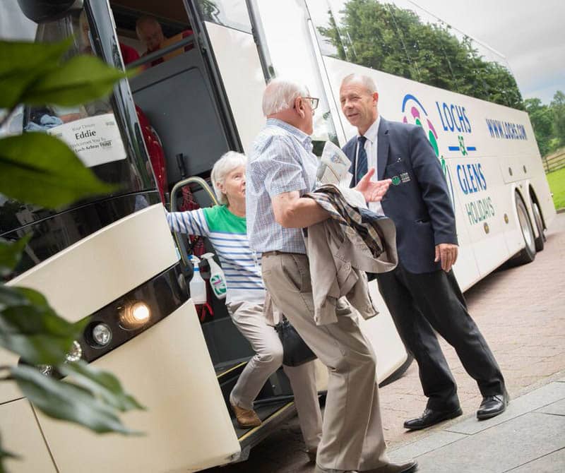 Luxury Coach Tour driver helping guests out of the coach on a holiday to Scotland