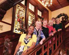 Six guests standing on the grand staircase inside the Highland Hotel, smiling and enjoying their stay