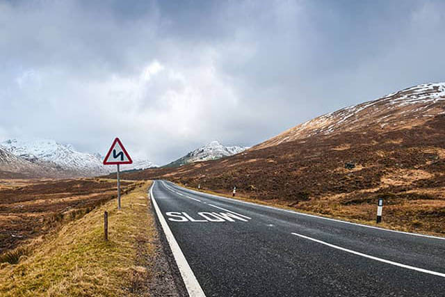 Vast mountains with snow and a quiet road in winter in the Glencoe area.