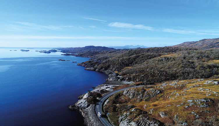 Scenic view across Loch nan Uamh with calm waters reflecting the surrounding hills and sky