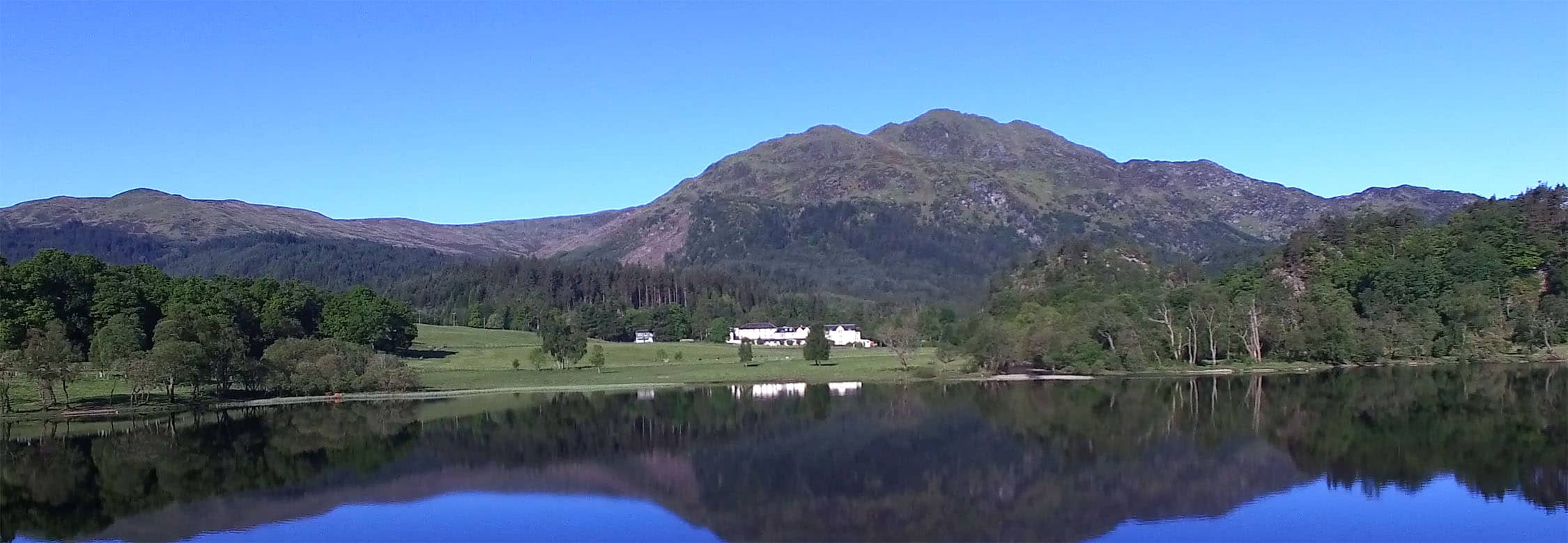 The view of the Loch Achray hotel from across the Loch on a summer's day.