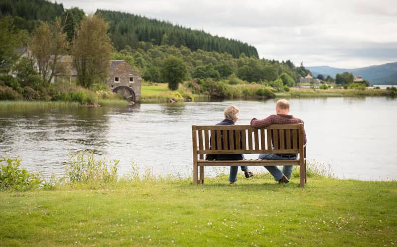 Two people seated on chairs enjoying the view outside Loch Tummel Hotel