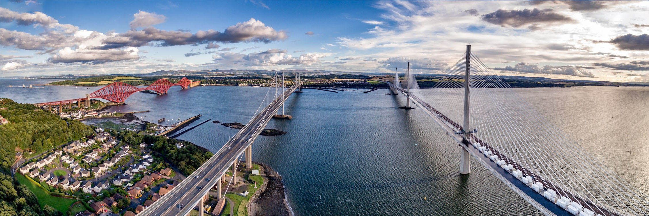 The historic Forth Bridge, with its distinctive red hue, stands proudly alongside its modern counterparts, the Forth Road Bridge and the Queensferry Crossing.