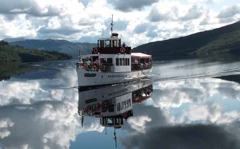 The Sir Walter Scott steamship gliding across the serene waters of Loch Katrine, surrounded by picturesque hills and lush forests.